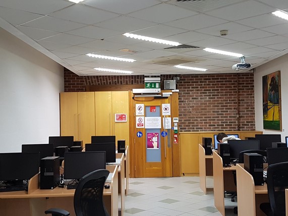 Photo of the inside of the Assitive Technology Service showing computer desks and a student sitting at one of them